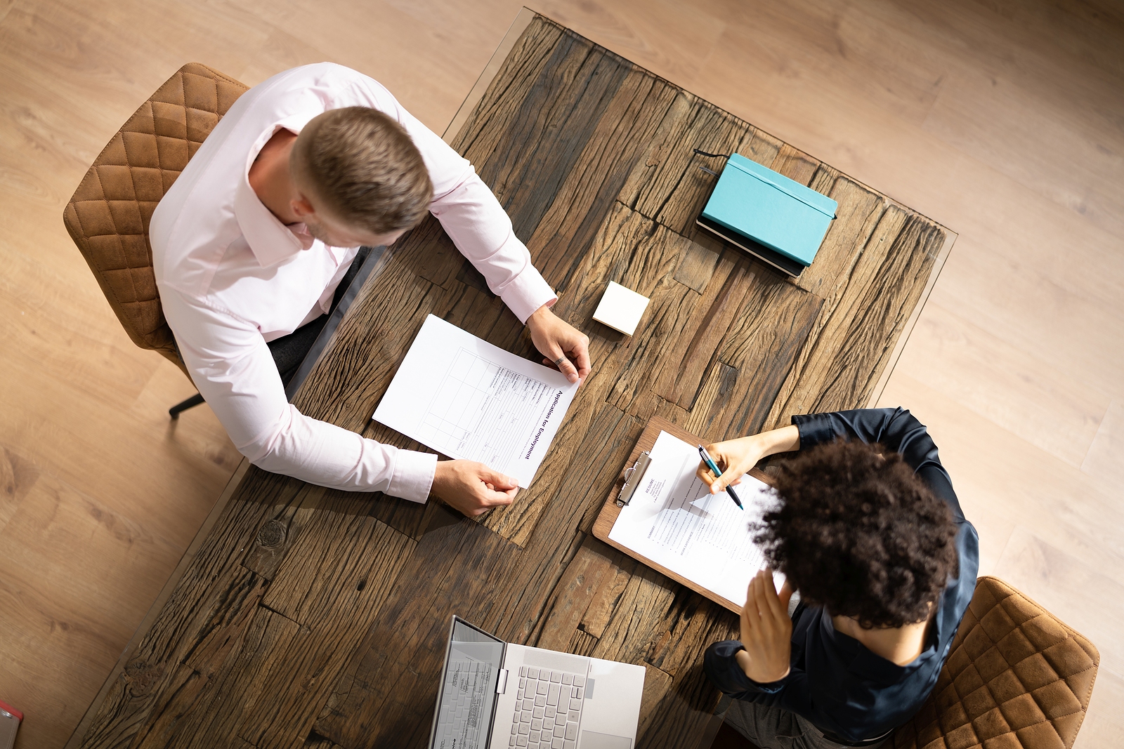 Overhead view of two people at table looking at resumes